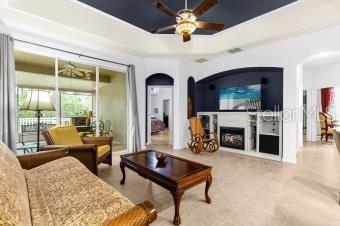 living area featuring a raised ceiling, arched walkways, ceiling fan, and a fireplace