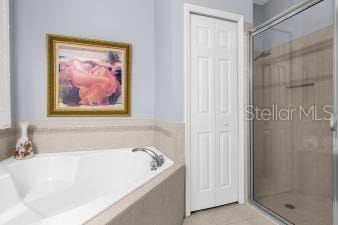 bathroom with a bath, a shower stall, and tile patterned flooring