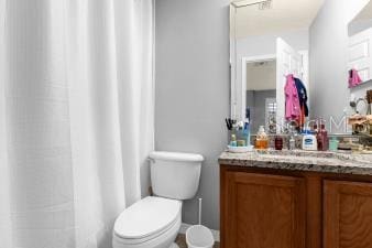 full bath featuring toilet, curtained shower, and vanity