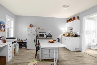 kitchen featuring visible vents, white appliances, white cabinetry, and light wood-style floors