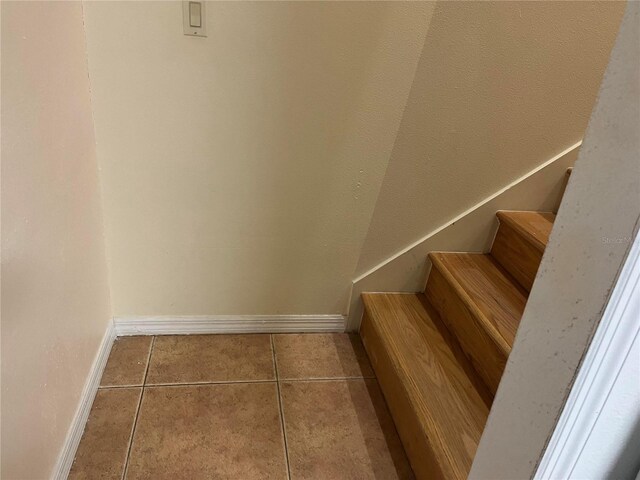 stairway with tile patterned floors and baseboards