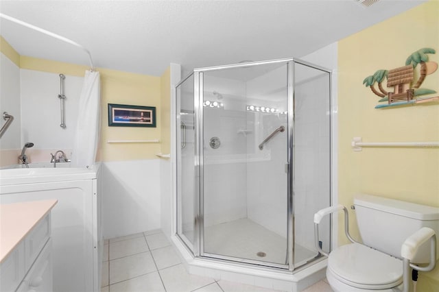 bathroom featuring washer / clothes dryer, tile patterned floors, vanity, toilet, and a shower with shower door