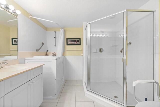 bathroom with a textured ceiling, tile patterned floors, vanity, and walk in shower