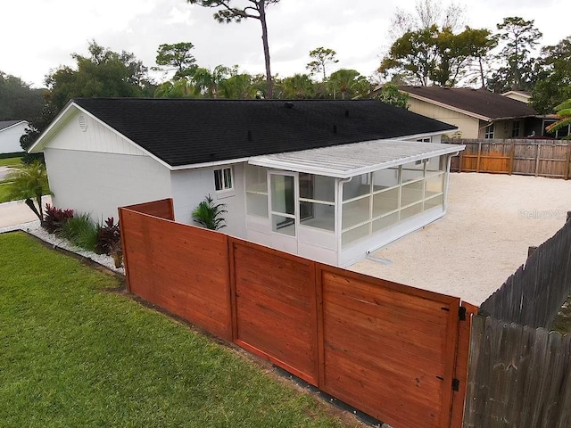 rear view of property with a sunroom and a lawn