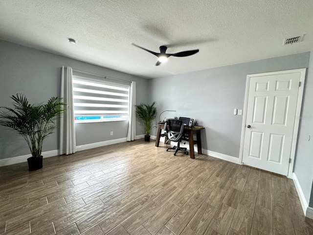 unfurnished office featuring hardwood / wood-style flooring, ceiling fan, and a textured ceiling