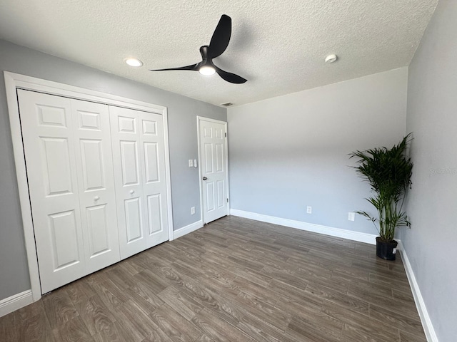 unfurnished bedroom featuring a closet, ceiling fan, dark wood-type flooring, and a textured ceiling