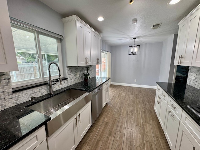 kitchen with sink, hanging light fixtures, white cabinets, and dishwasher