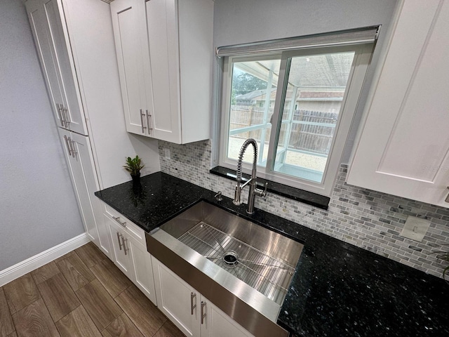 kitchen featuring decorative backsplash, sink, white cabinets, and dark stone countertops