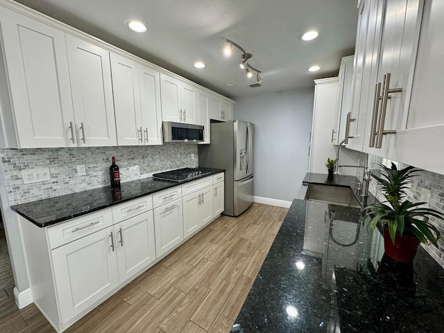 kitchen featuring white cabinets, dark stone countertops, light hardwood / wood-style flooring, and appliances with stainless steel finishes