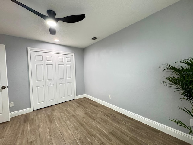 unfurnished bedroom featuring ceiling fan, hardwood / wood-style floors, and a closet