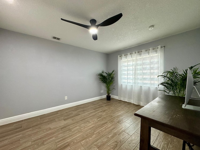 empty room with hardwood / wood-style flooring, a textured ceiling, and ceiling fan