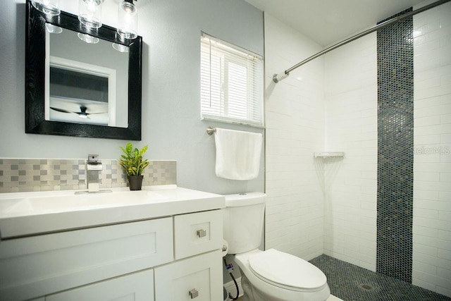 bathroom with backsplash, toilet, tiled shower, and vanity