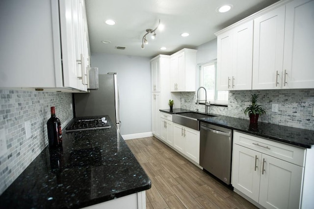 kitchen with dishwasher, white cabinetry, decorative backsplash, sink, and light wood-type flooring