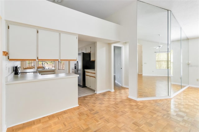 kitchen with sink, ceiling fan, white cabinetry, kitchen peninsula, and light parquet flooring