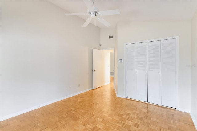 unfurnished bedroom with ceiling fan, high vaulted ceiling, a closet, and light parquet floors