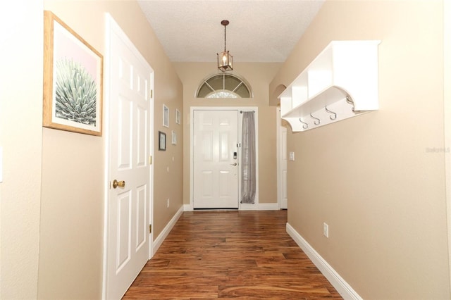 doorway with dark wood-type flooring and a textured ceiling