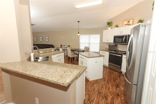 kitchen with pendant lighting, sink, stainless steel appliances, a center island, and kitchen peninsula