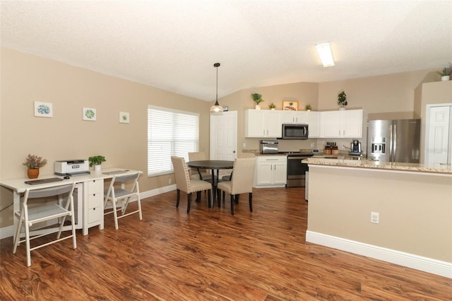 kitchen featuring vaulted ceiling, appliances with stainless steel finishes, pendant lighting, white cabinets, and dark wood-type flooring