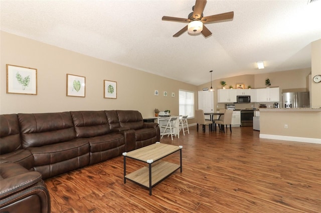 living room with ceiling fan, dark hardwood / wood-style floors, vaulted ceiling, and a textured ceiling