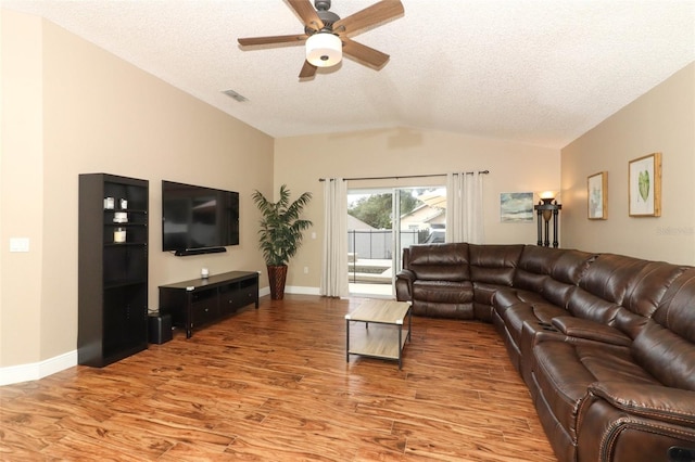 living room with ceiling fan, wood-type flooring, vaulted ceiling, and a textured ceiling