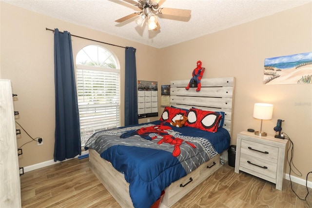 bedroom with ceiling fan, hardwood / wood-style floors, and a textured ceiling