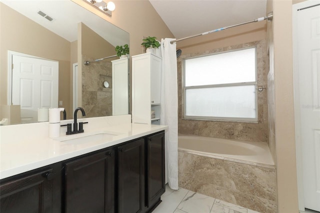 bathroom featuring vanity, tiled shower / bath combo, and vaulted ceiling