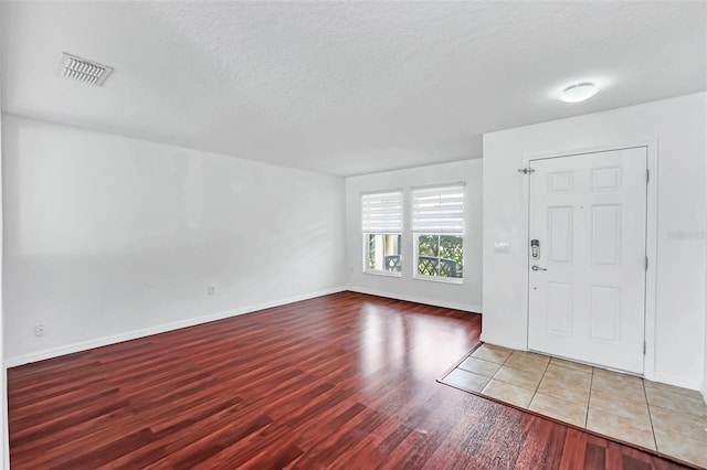 foyer entrance with wood-type flooring and a textured ceiling