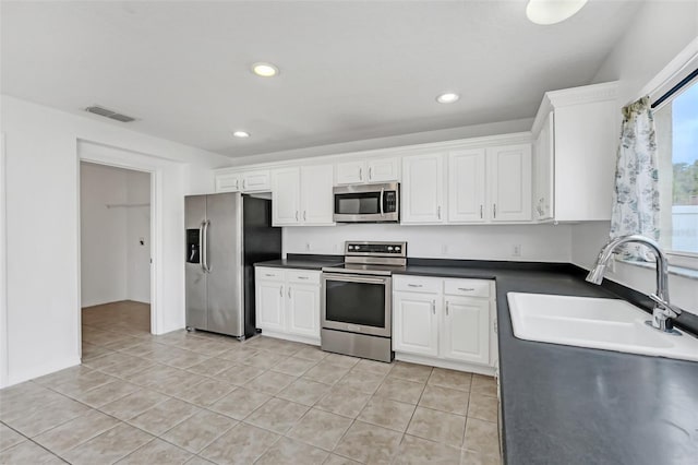 kitchen with light tile patterned floors, sink, white cabinets, and stainless steel appliances