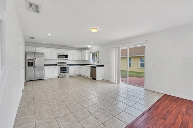 kitchen with sink, stainless steel appliances, white cabinetry, and light tile patterned floors