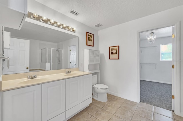 bathroom featuring toilet, a textured ceiling, an enclosed shower, tile patterned floors, and vanity