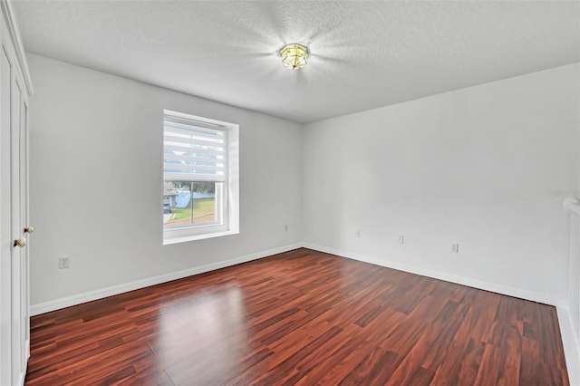 unfurnished room featuring a textured ceiling and dark hardwood / wood-style flooring