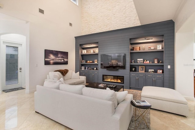 living room with built in features, a high ceiling, and a large fireplace