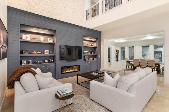 living room featuring a fireplace, built in features, and a high ceiling