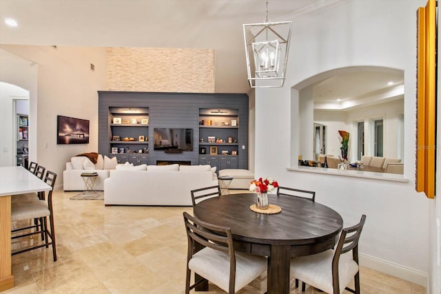 dining space with built in shelves, a notable chandelier, and a raised ceiling