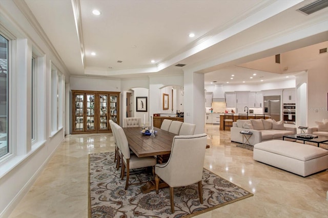 dining room featuring sink, crown molding, and a raised ceiling