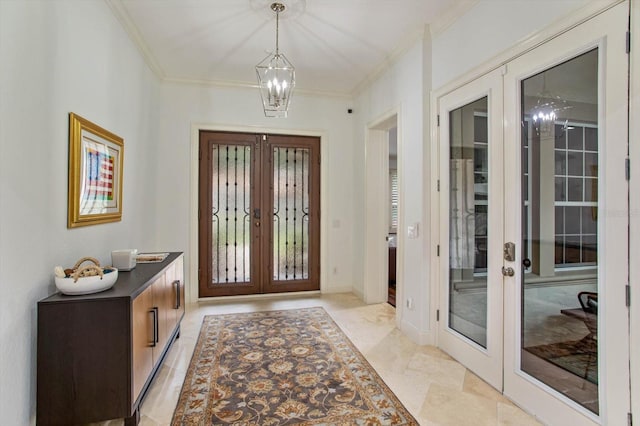 foyer entrance with ornamental molding, french doors, and an inviting chandelier