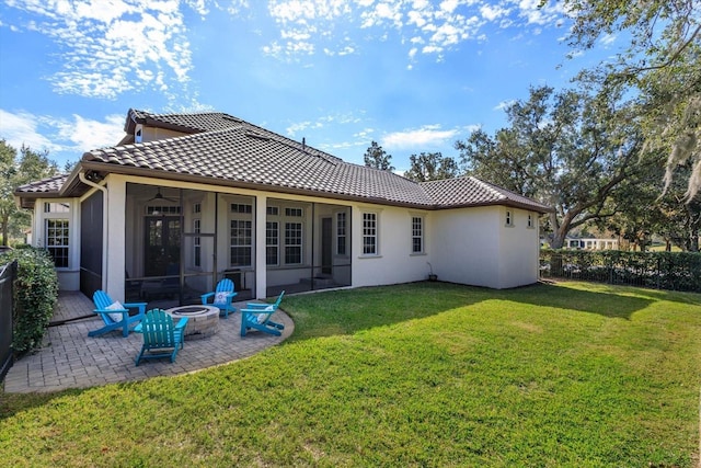 back of house featuring an outdoor fire pit, a lawn, ceiling fan, and a patio