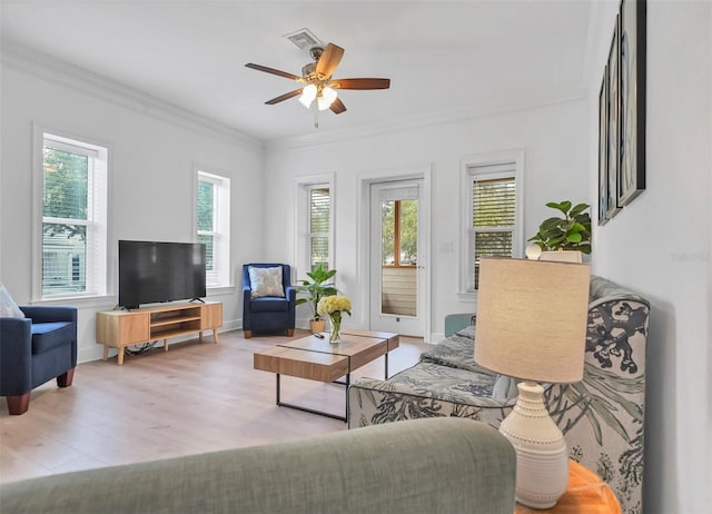 living room with a healthy amount of sunlight, light hardwood / wood-style floors, and ornamental molding