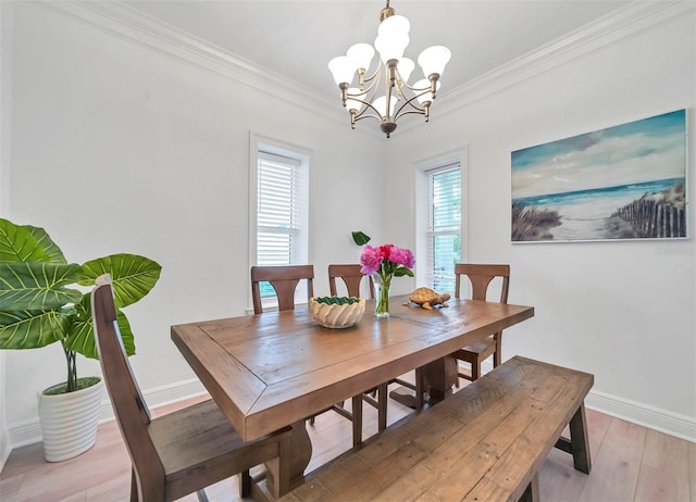 dining space with light hardwood / wood-style floors, ornamental molding, and a chandelier