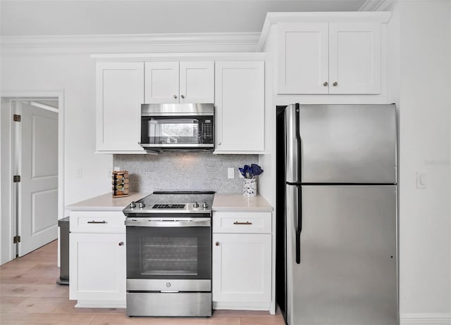 kitchen with ornamental molding, white cabinets, backsplash, and appliances with stainless steel finishes