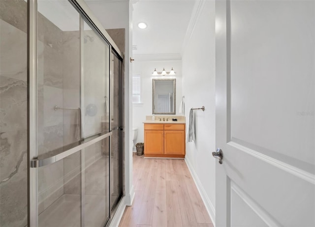 bathroom featuring hardwood / wood-style floors, toilet, walk in shower, vanity, and ornamental molding