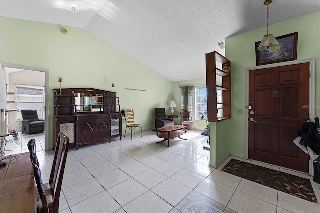 foyer with lofted ceiling, a textured ceiling, and light tile patterned floors