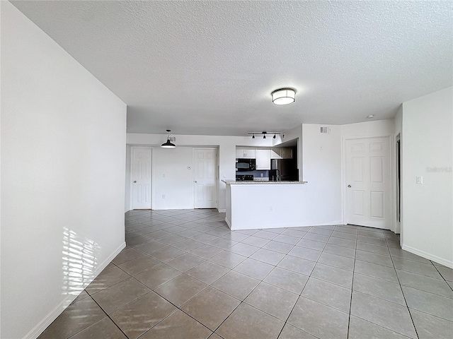 unfurnished living room with tile patterned flooring and a textured ceiling