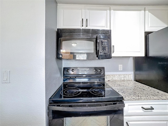 kitchen with white cabinetry, light stone countertops, and black appliances