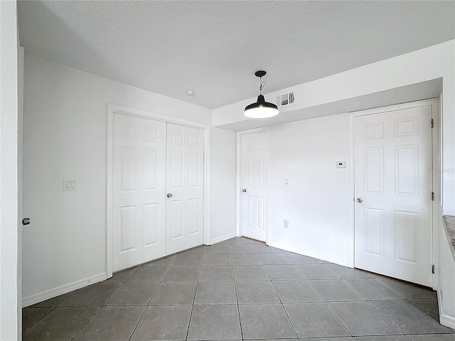 unfurnished bedroom with dark tile patterned floors, a textured ceiling, and a closet