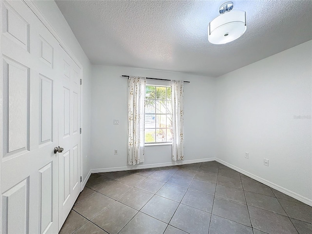 tiled spare room with a textured ceiling