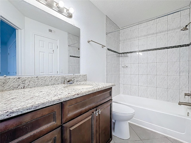 full bathroom featuring toilet, a textured ceiling, vanity, tiled shower / bath combo, and tile patterned flooring