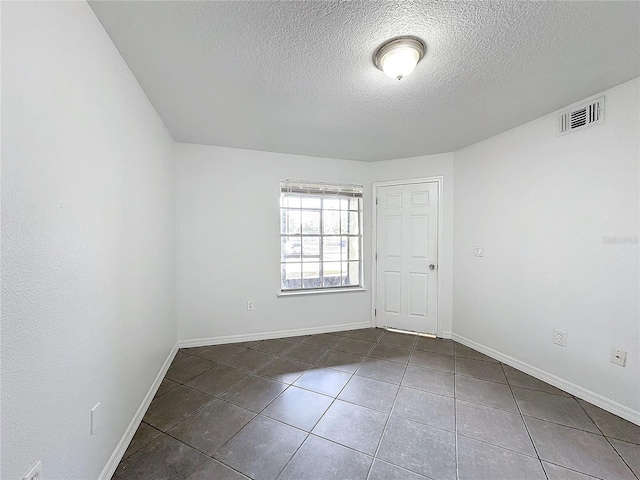 unfurnished room featuring dark tile patterned flooring and a textured ceiling