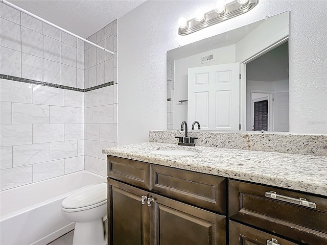 full bathroom featuring tiled shower / bath combo, vanity, a textured ceiling, and toilet