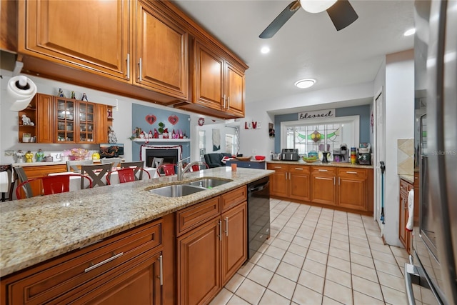 kitchen featuring sink, light tile patterned floors, stainless steel refrigerator, black dishwasher, and light stone counters